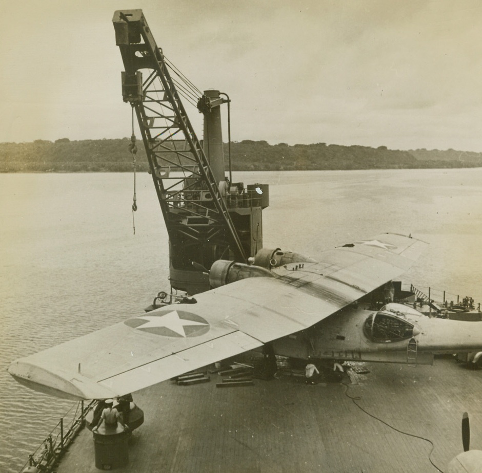 U.S. AIRCRAFT GARAGE AT SEA, 2/12/1943. SOUTH PACIFIC—Expert repair crews aboard “The Seaplane Tender” go to work on a PBY which has just been lowered to the after deck. The huge vessel, based in the South Pacific, contains hangars, shops, and equipment for the complete overhaul of the PBY’s  which are used to search enemy waters, bomb or torpedo enemy surface ships, scout Jap task forces, or patrol our bases for enemy subs. Pilots and crews live aboard the vessel which boasts a barber shop, soda fountain, canteen and laundry.  Credit: ACME.;