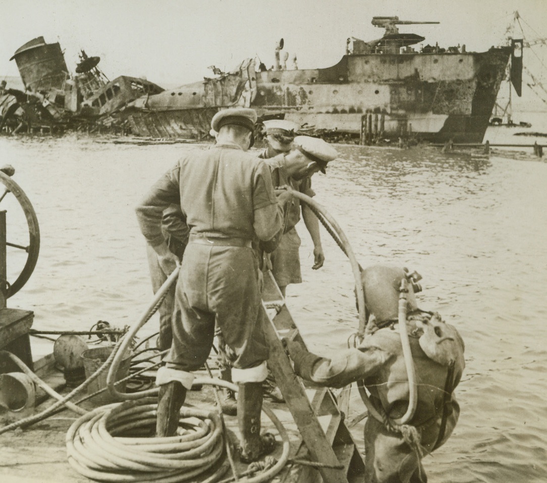 Capture - - Then Clean Up, 3/14/1943. Tobruk, Libya - - In Tobruk harbor, a British diver goes down under to inspect the wreck of an Italian tanked blasted by U.S. Liberator planes.  The distorted wreckage of a freighter further clutters the valuable port.  The rule of North African warfare has been: capture clean-up and use. Now, Tobruk is a busy allied supply base handling shipments for British and Americans maneuvering to close in on wily Rommel. Credit line (ACME);