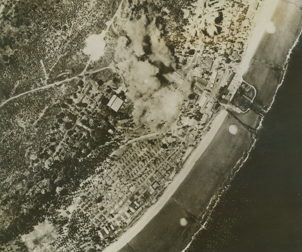 Bombs Over Naru, 5/28/1943. Thick smoke clouds rise from Jap phosphate works on Nauru Island as American bombs find their mark on that South Pacific island which lies in the Gilbert Island group Northeast of Guadalcanal.  Five to seven Japanese Zeros were shot down in the Nauru raid, with no American planes lost.  Funafuti, largest of the Ellice Islands, which was occupied by American forces in April, served as a base for the raiders.Credit (U.S. Army Air Forces photo from ACME);