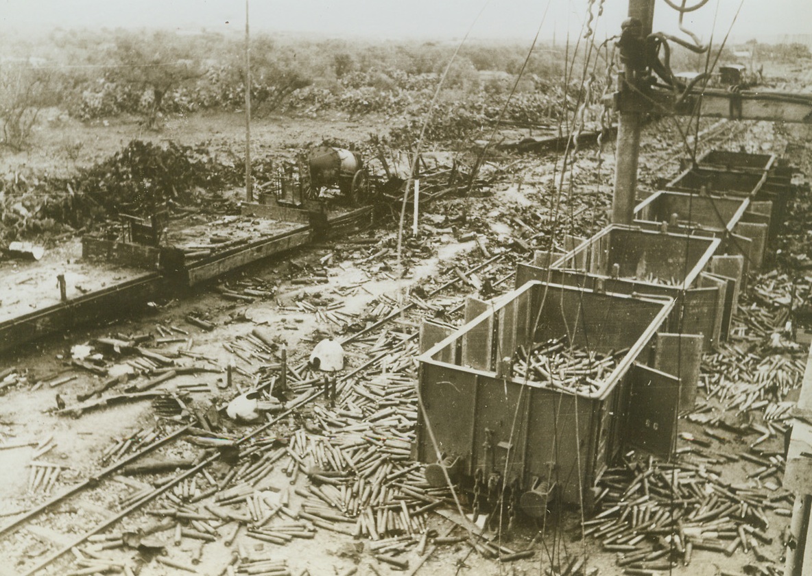 Bullets the Axis Didn’t Use, 5/26/1943. Enfidaville, Tunisia—Scattered beside the wrecked train are shells blown out of a railway car by Allied dive bombers making an attack on Enfidaville during the drive on Tunis. The fury and exactness  of Allied air attacks on enemy supplies and communications played a major part in the capture of North Africa from the Axis.Credit: ACME.;