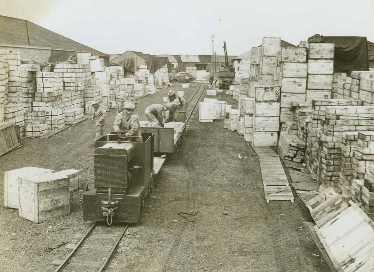 American Railroad in England, 5/22/1943. Somewhere in England -- American soldiers stack crates of supplies on a car that runs along the only U.S.-built and operated railroad in England. Covering 17 miles of trackage, the railroad was built by the Army to haul supplies from the British unloading point to the warehouses, or from U.S. warehouses to British lines for shipment. Credit: ACME;