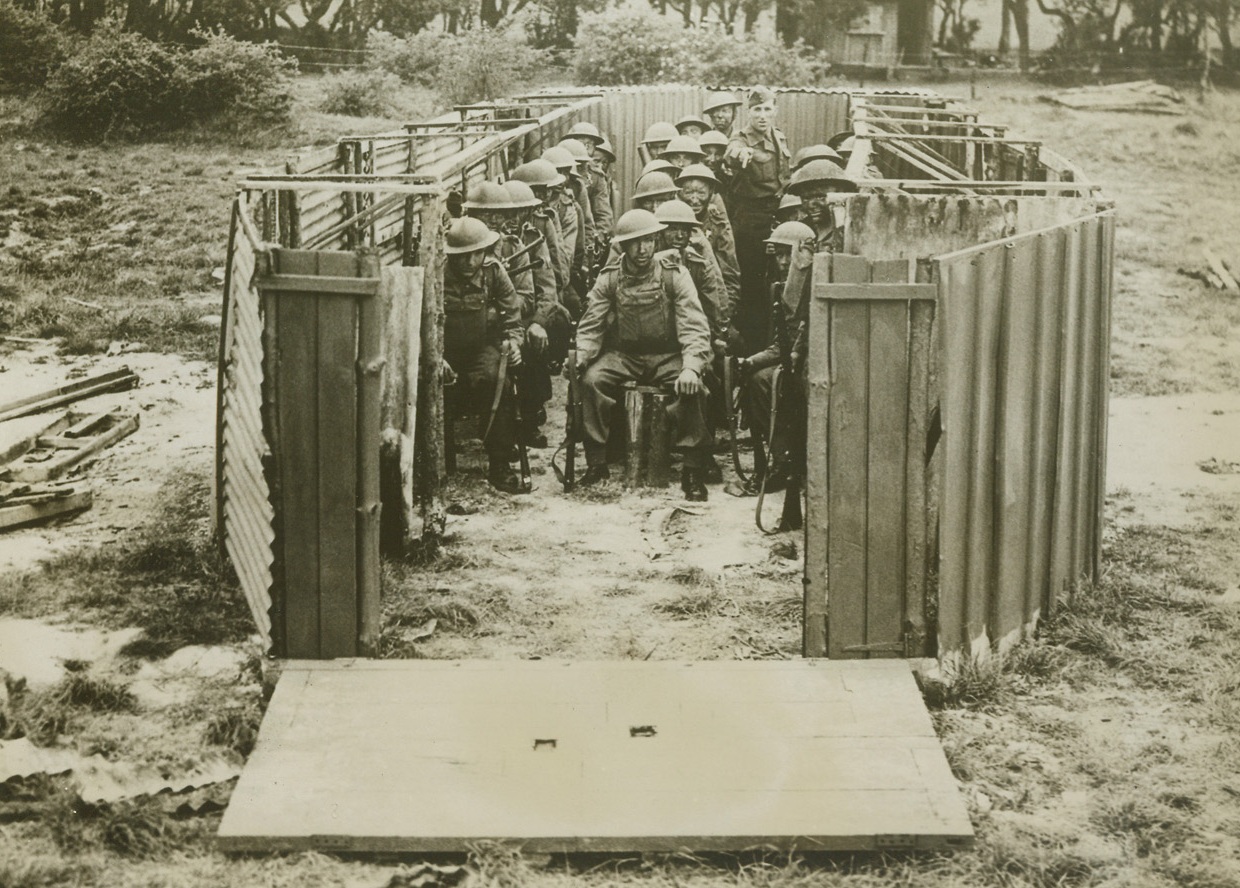 DRY LANDING, 5/24/1943. SOMEWHERE IN ENGLAND – All set for invasion and no place to invade is the predicament of these royal Marines who are ready to pile out of a landing barge built on dry land.  With their faces blackened, they receive instructions from an officer on the “invasion” craft in Southern England.  These fighters, undergoing the toughest of training, hope to be the first Allied troops to set foot on the European continent.  Credit: Acme;