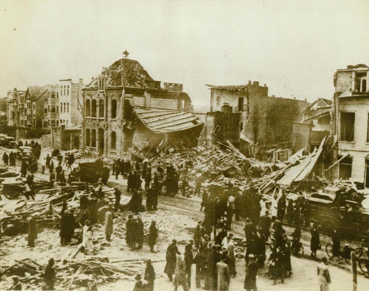 After Our Bombers Left, 5/20/1943. Antwerp—Rushing from their shelters as the “all clear” sounds, civilians throng in the streets of Antwerp to survey the damage done by American bombers in their devastating daylight raid. Photo was recently received in England through a neutral source. 3/20/43 (ACME;