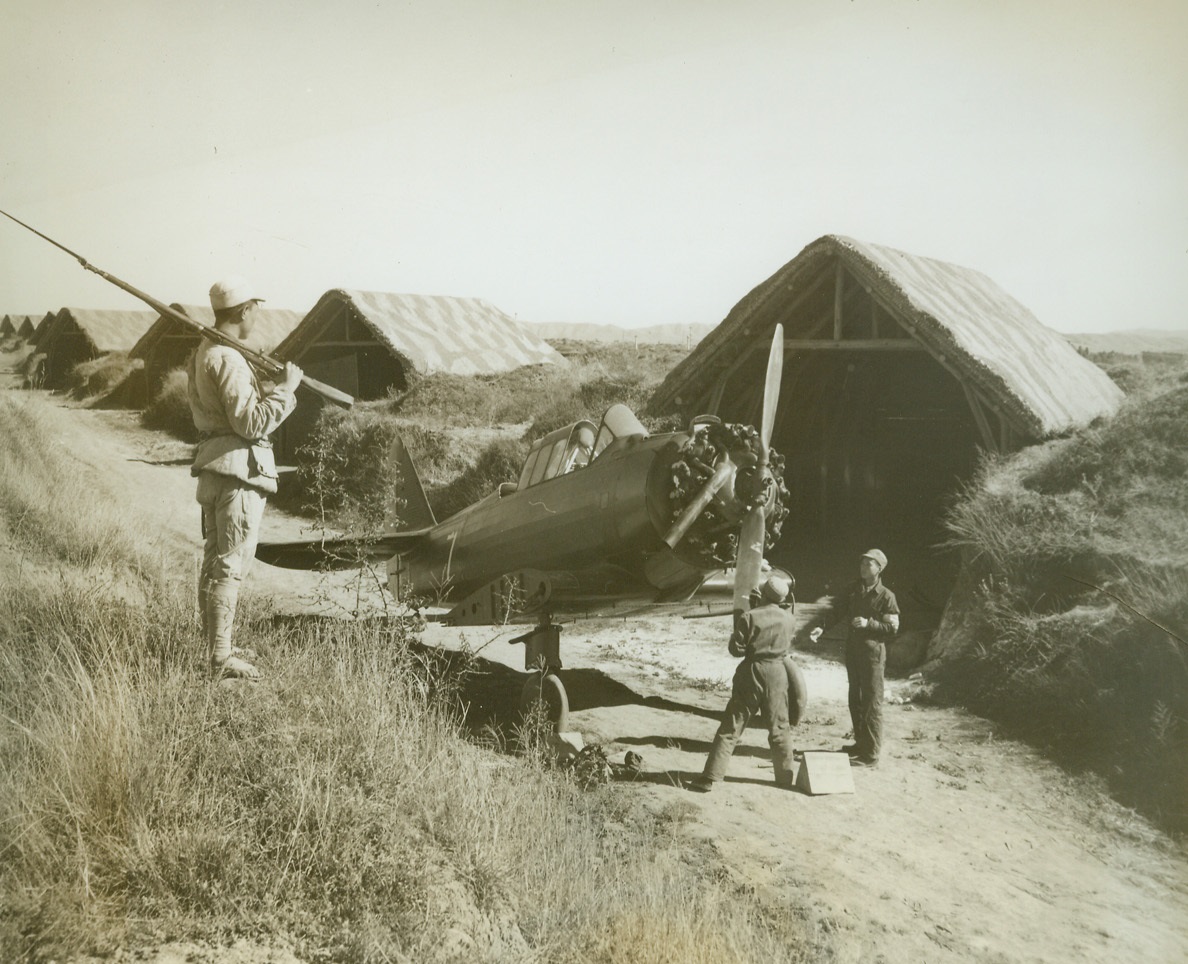 Camouflaged Huts House Fighter Ships in China, 1/13/1943. Somewhere in China – A Chinese soldiers stands guard as repair work is started on a U.S. fighter plane.  Planes are stored in these concealed buildings of a Chinese dispersal area. Credit line (ACME);