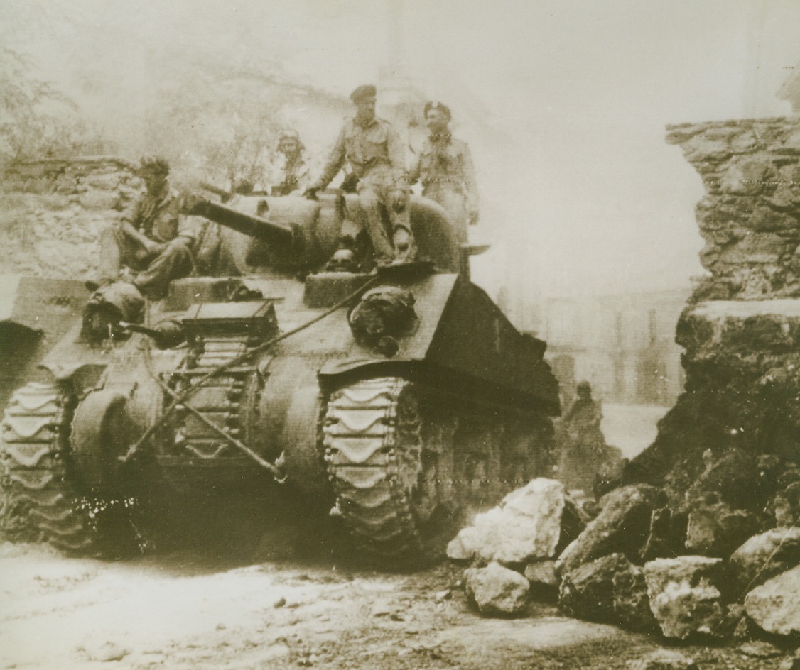 The 8th Army Forges Ahead, 9/22/1943. An American-built Gen. Sherman tank manned by a crew of the British 8th Army passes through a road block at Nicastro, Italy, as British forces pushed their way to the north to join the U.S. 5th Army. Today, the Allies are closing in on Naples having driven into the last mountain barrier before the blazing city.  Credit: OWI radiophoto from ACME.;