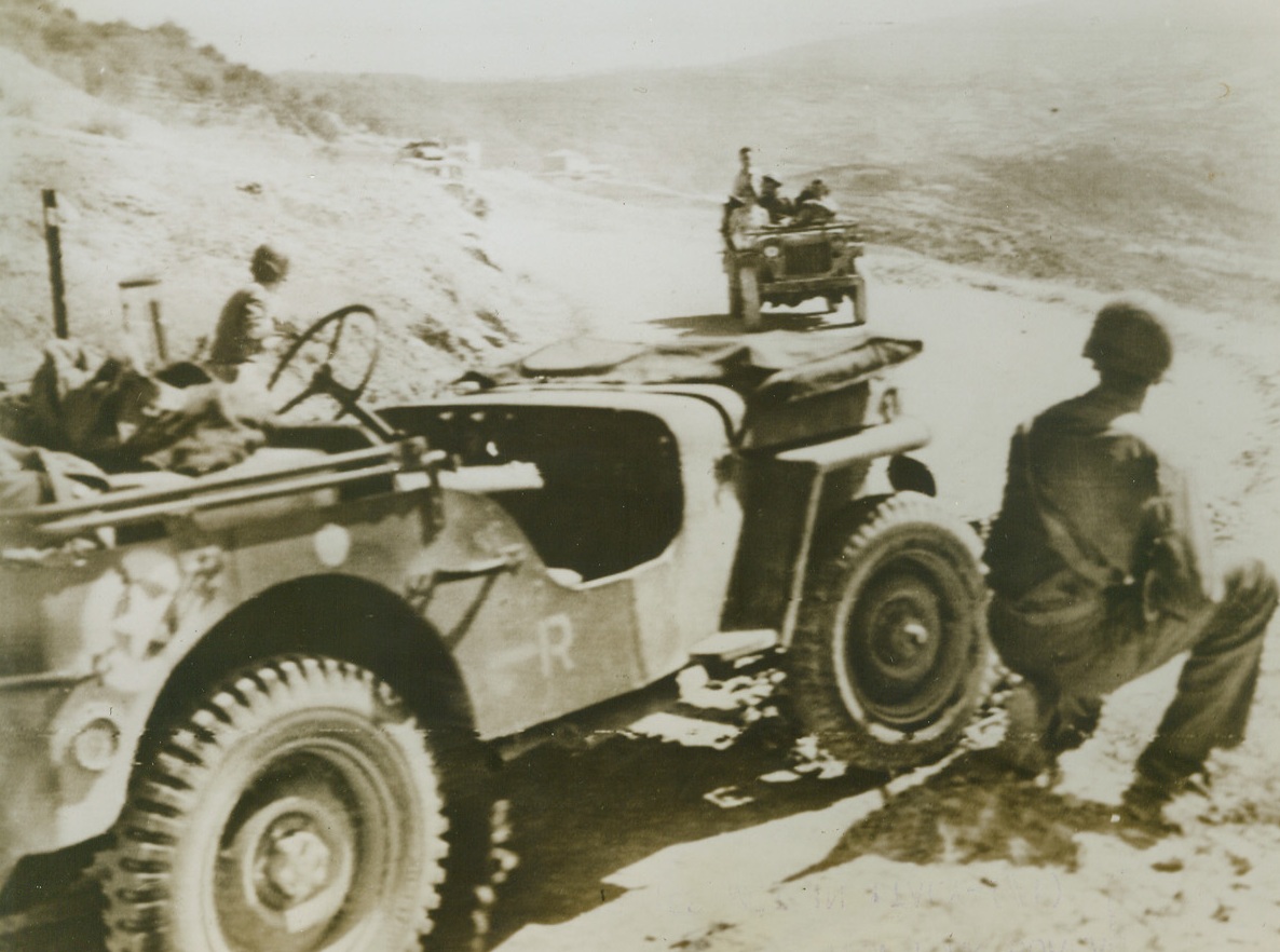 As 5th and 8th Armies met in Italy (#1), 9/22/1943. Italy—This alert U.S. 5th Army Platoon, (in foreground), took no chances when they sighted cars filled with what appeared to be British soldiers driving toward them along this road in Italy. They blocked the road, their guns ready, and stopped the strangers only to find they were an advanced patrol of the British 8th Army which had driven from the south of Italy to meet the American forces in the Salerno area. Thus, the forces of Gen. Clark and Gen. Montgomery met. (Also see ACME photo #RW698607). Credit: U.S. Signal Corps radiotelephoto from ACME.;