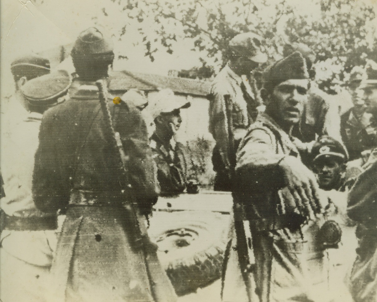 Nazis Seize Rome, 9/19/1943. The German caption, accompanying this photo in a Berlin newspaper, say that the Nazi officer (right, between soldiers), who is seated in a small armored care, is “discussing” the capitulation of Rome with Italian soldiers. Listening to the one-sided “discussion” is another German officer, behind the car, and a Nazi soldier who wears a white cap and thinks things over, chin in hand. Credit: ACME RADIOPHOTO.;