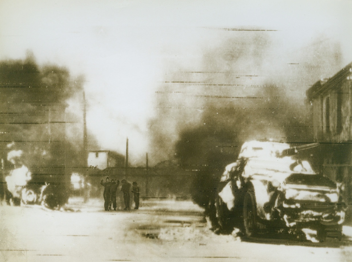 BATTLE SMOKE CLOUDS ROME, 9/16/1943. ROME—After swooping down to the suburbs of Rome, following Italy’s capitulation to the Allies, Nazi parachute troops disarm an Italian tank crew in the street, according to the German caption that accompanied this radiophoto. Smoke and flame rise over the Italian city from fires set by the Nazis. Photo was sent from Berlin to Stockholm and radioed to New York today (Sept. 16th). Credit: Acme radiophoto;