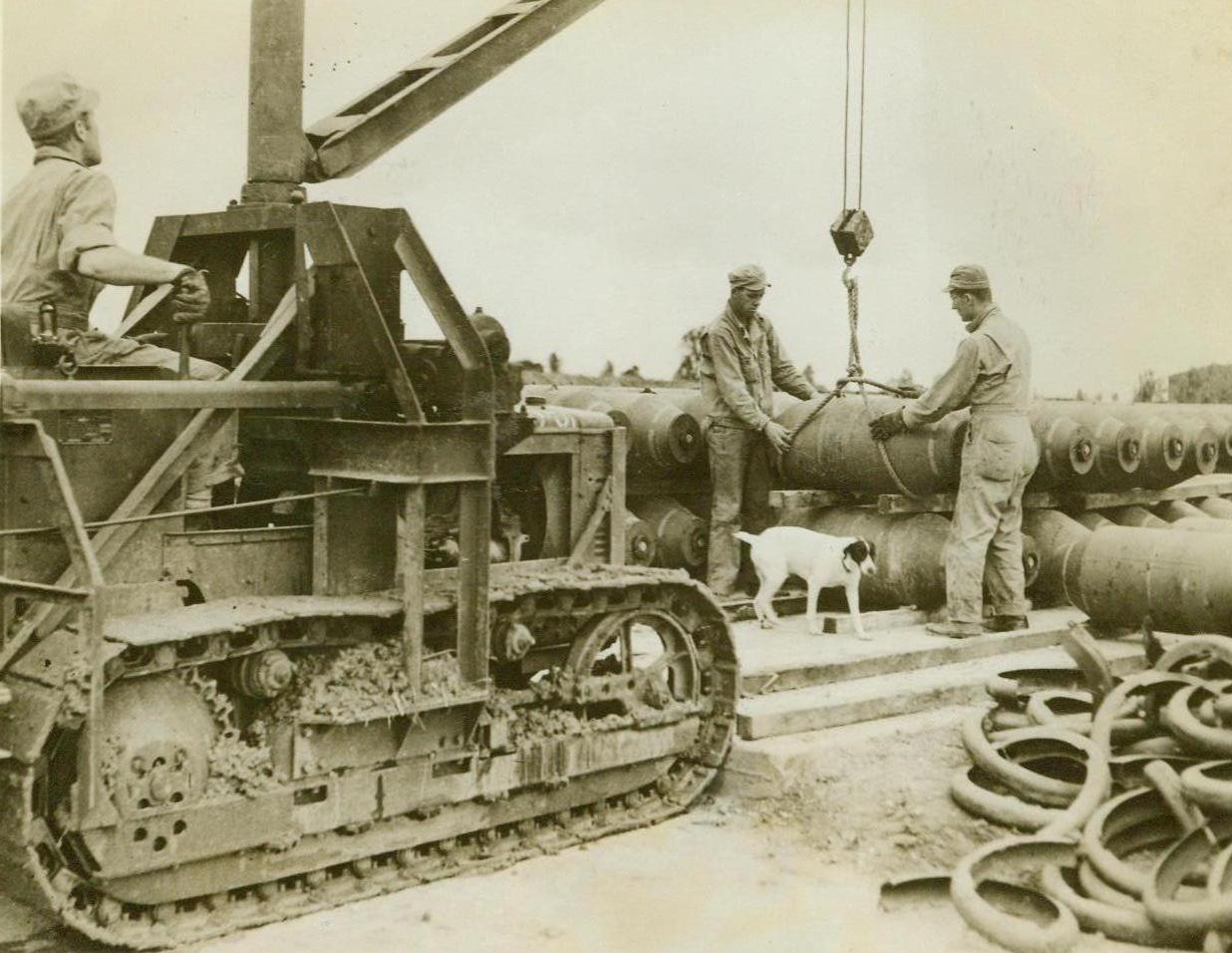 Preparations For A Raid, 9/19/1943. Somewhere In England - Destined to mess up enemy territory, these bombs are picked up by a tractor that will place them in a loading wagon. The deadly missiles will soon travel over Europe in the bomb racks of B-26 Marauders. The white pup “assisting” in operations is one of the mascots at this U.S. Marauder Base in England. Credit: ACME;