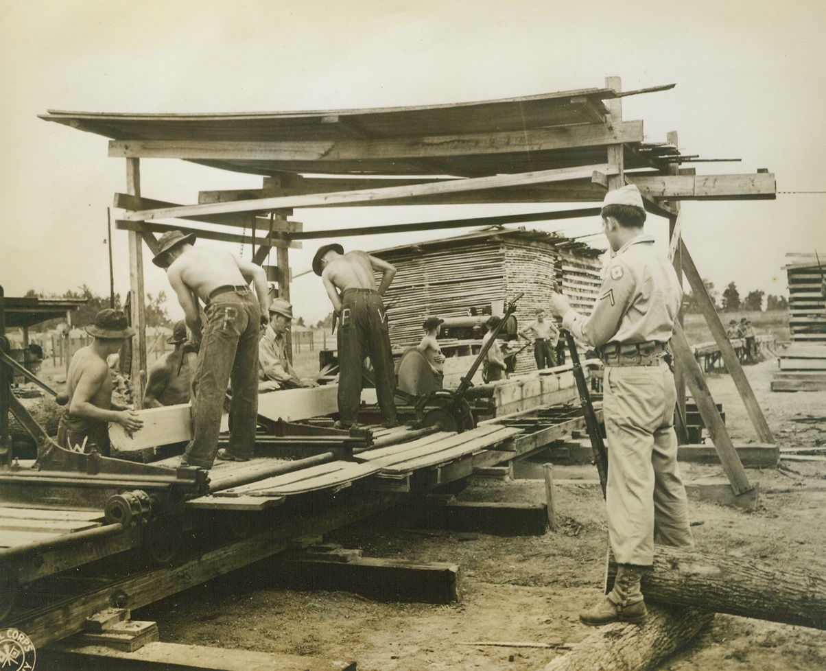 LIFE AT THE LARGEST NAZI PRISONER OF WAR CAMP, 10/4/1943. ALICEVILLE, ALA.—Thousands of German prisoners now occupy miles and miles of guarded territory at Aliceville, Alabama, at the country’s largest internment camp for captured Nazis. Tennis courts, badminton and various ball game facilities are available between the barracks within each compound that contains 1,000 prisoners. A contest in landscaping resulted in beautifully kept green lawns, sculptured animals and patterned flower gardens, while the opportunity to build exercise aids led to the erection of horizontal bars, broad-jump pits and shot-put courses. Very few Nazis have tried to escape, and not one has succeeded. These photos whow a few typical scenes at the Aliceville internment camp. With as many as 1,500 prisoners of war out working at one time, the Germans seem especially fitted for saw-mill jobs. A U.S. soldier guards this group of “lumberers” who receive 80 cents apiece for canteen credits out of the $2.50 a day paid the government.Credit: U.S. Army Signal Corps photo from Acme;