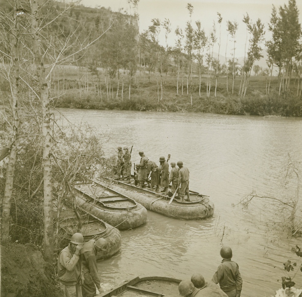 Nazi Italy Morale Drowned in the Volturno, 10/25/1943. ITALY -- When 5th Army troops splashed, paddled, or swam across the Volturno, more than a river was lost to the Germans. The Nazis learned in blood that their natural barrier defense system wouldn't work. To further consolidate this message of Axis defeat, crack American engineers immediately floated a pontoon bridge across the shallow river so that heavy Allied equipment could rumble on the heels of the advanced infantry forces who had begun the job of dislodging the enemy. These photos tell the story of that bridge which, in reality, may be called a road to victory in Italy for the Allies. New York Bureau Construction gets under way on the main 5th Army bridge spanning the Volturno as engineers begin placing pontoon sections. Credit (ACME Photo by Bert Brandt, War Pool Correspondent);