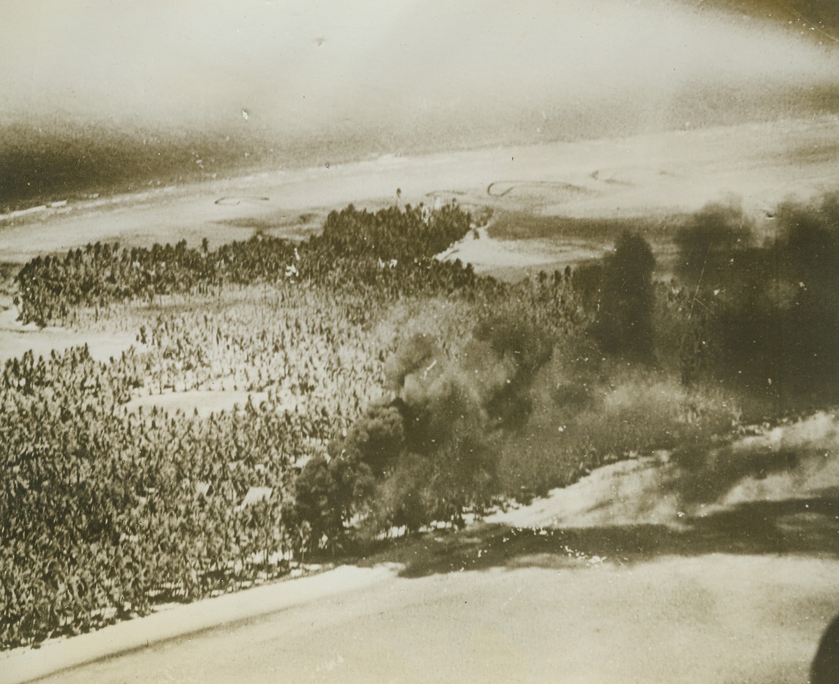 Blasting Tarawa, 10/8/1943. Smoke billows from battered Jap installations during the combined Army-Navy raid on Tarawa Island in the Marshall-Gilbert group on September 18th. One of the Navy planes that flew from Carrier decks to raid the Jap outpost flew so low for strafing activity that it returned with palm fronds clinging to the fuselage.Credit: Official U.S. Navy photo from ACME;