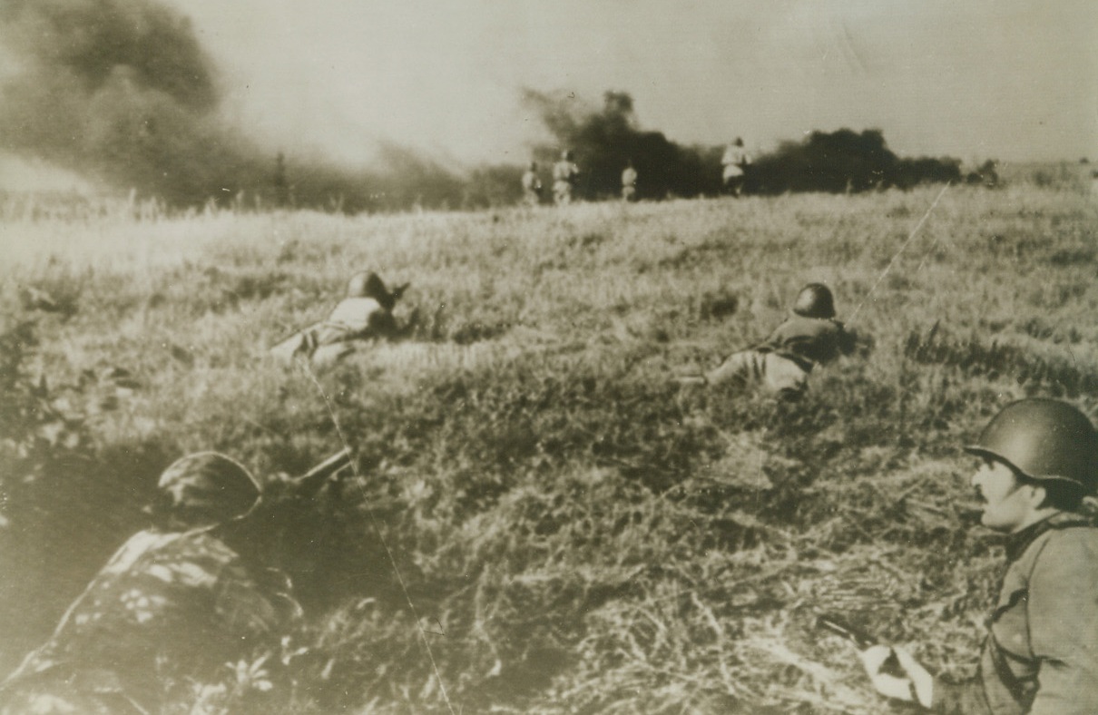 Red Army Attacks, 10/15/1943. ON THE RUSSIAN FRONT—Captain Gadabadze’s company makes its way through thick grass as it attacks German positions near the Dnieper. Latest reports from the Soviet front indicate that the Red Army stormed and captured Zaporozhe, industrial strong point on the east bank of the Dnieper River bend, breaking German southern defenses and opening the way for a Russian drive into the Crimea. Credit: ACME Radiophoto;