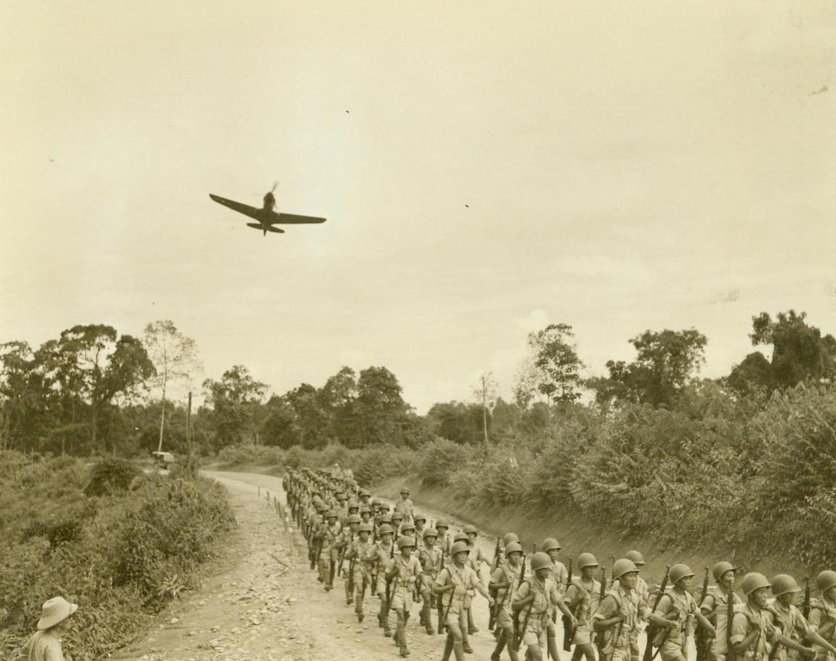 Along The Tokio Road, 10/14/1943. CBI Theater – With American P-40s giving them top cover, U.S. Army-trained Chinese troops march down the “Tokio Road.” The new highway, leading from India to China, was given the nickname by the Americans who built it. For the first time in history, American and Chinese soldiers are battling side by side against the common enemy. Each unit of the front-line Chinese force is accompanied by American officers and observers. 10/14/43 (ACME photo by Frank Cancellare, War Pool Correspondent);