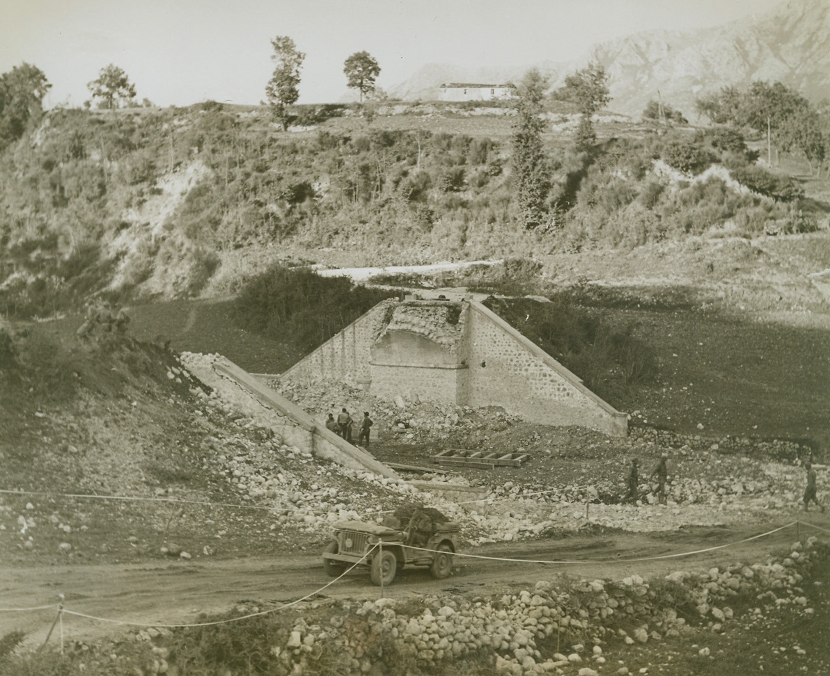 Nazi Inspired Detour, 11/19/1943. ITALY – The Fifth Army in Italy disproves an old proverb by not crossing its bridges even after it comes to them. By dynamiting this bridge, the retreating Nazis forced the Americans to cross a filled-in ravine and climb a steep by-pass before they could regain the road that leads to the front. The bridge formerly spanned the ravine.  Credit (ACME Photo by Bert Brandt, War Pool Correspondent;