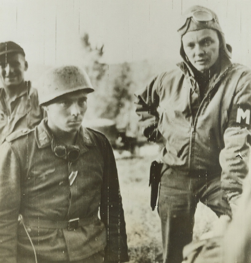 Take Me, 11/5/1943. Not only did this Nazi paratrooper (left) beg to be captured, he jumped on the motorcycle of MP Private Bjorlin, of Duluth, Minn. To make certain he wouldn’t be left behind. The Germans in Italy have good reason to be tired of war, for their defense lines crumble almost as fast as they fashion them. Credit: ACME PHOTO VIA ARMY SIGNAL CORPS.;