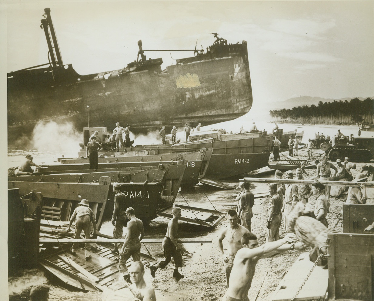 Japs Contribute "Breakwater" for Harbor, 11/10/1943. SOLOMONS -- When U.S. Forces blasted the Nip ship the Kinugawa Maru, it was conveniently beached on this Solomon Island forming a breakwater and sheltering landings by Allied Forces. Here, in the shadow of the Jap vessel's burned out hulk, U.S. Coast Guardsmen unload lumber and other supplies, brought ashore from a transport by landing craft.  Credit: (U.S. Coast Guard Photo from ACME);