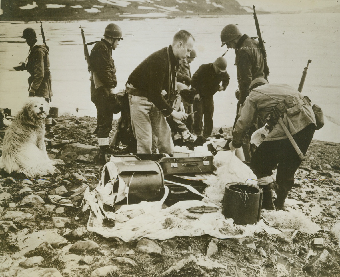 German Weather Base Destroyed, 11/9/1943. Secretary of the Navy Frank Knox today revealed that a powerful German radio and weather base on an island off Greenland, had been taken and destroyed by U.S. Forces and two prisoners taken. This is the second time in recent months that such a base has been captured in Greenland waters. Here, U.S. Coast Guardsmen and soldiers, members of the combined force that destroyed the base, examine an abandoned Nazi parachute kit found on the site. Food, hand grenades, and other material were left behind by the Nazis, who presumably escaped by plane.Credit: (U.S. Coast Guard Photo from ACME);