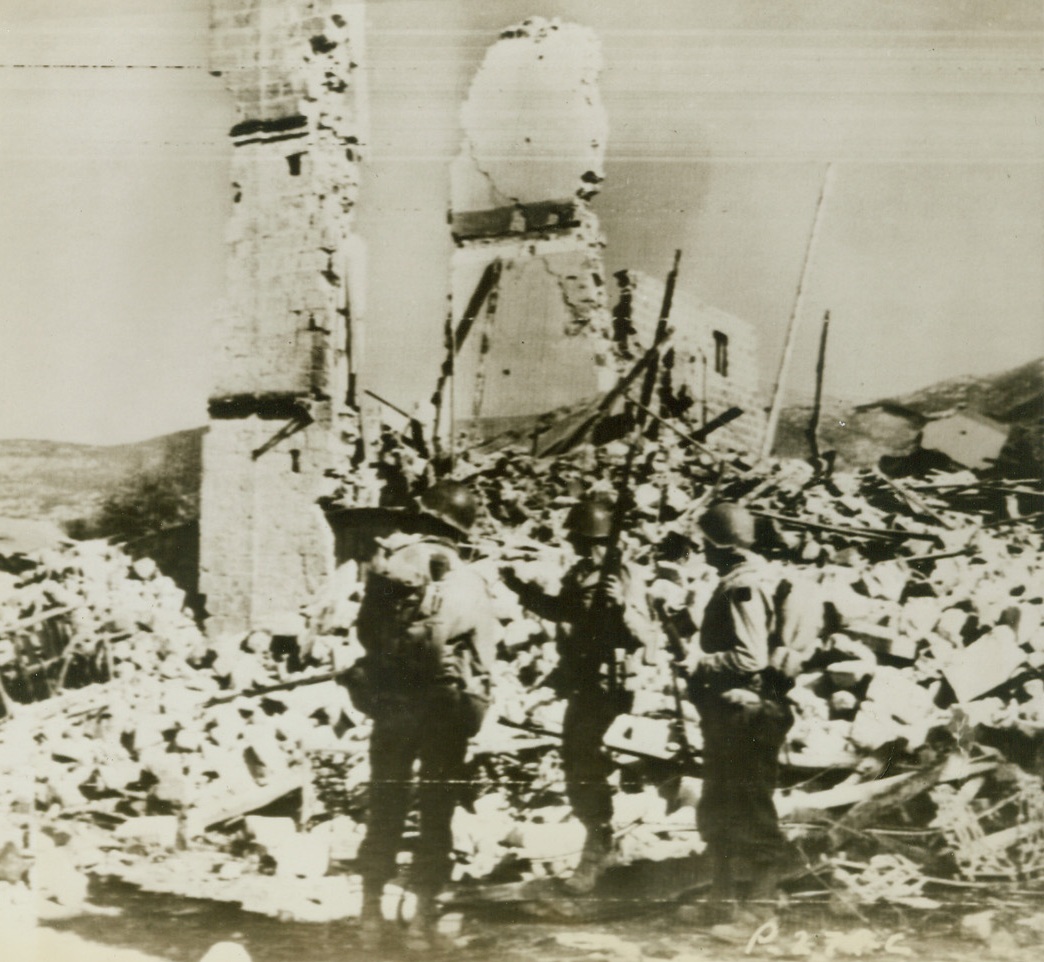 AMERICANS ON PATROL IN ITALY, 11/16/1943. MIGNANO, ITALY—Three United States soldiers patrol the outskirts of Mignano, leveled by American and German artillery fire. The populace of the town fled when the withering barrages began, and hid in caves in nearby hills. Credit Line (U.S. Army Radiotelephoto from ACME);