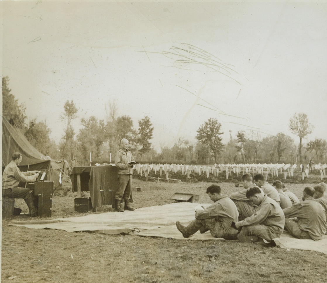 Prayer for Lost Comrades, 12/19/1943. Italy – Close to the graves they tend, Allied Fifth Army soldiers bow their heads in prayers led by Capt. Christ A. Lehne, Chaplain of Fredericksburg, Texas. In the background, other service men erect crosses and tidy the final resting places of Americans who died in battle. Credit: (ACME);