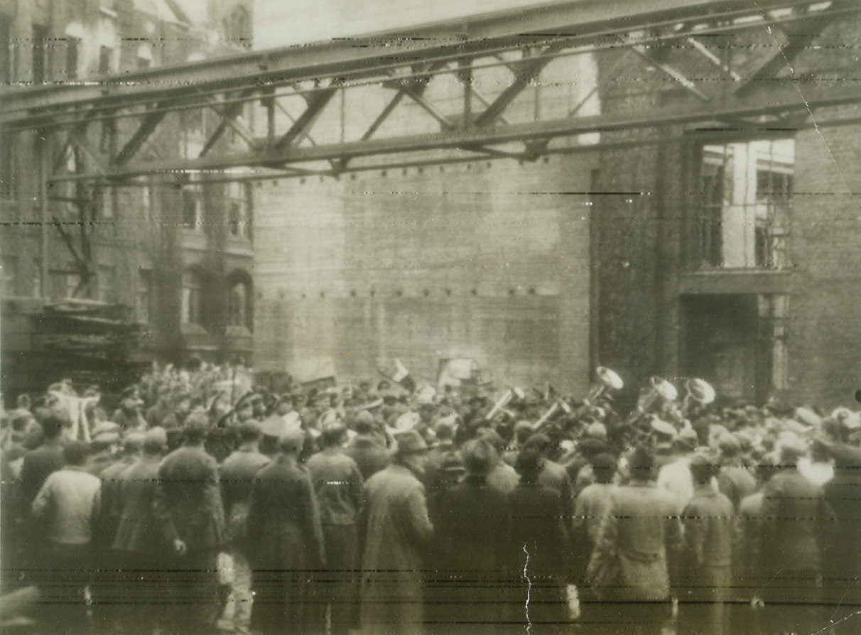 Blowing Up Morale, 12/11/1943.BERLIN—German workers stand around looking glum as a Nazi military band gives an impromptu, morale-boosting concert, outside a large factory that suffered serious damage in the recent bombings of Berlin. Photo, radioed to New York today (Dec. 11th), was obtained through a neutral source. Credit Line (ACME Radiophoto);