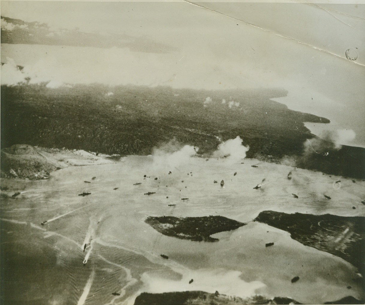 We Nab 20 Jap Warships, 12/6/1943. While smaller ships scuttle, beetle-like for the open sea, flames rise from what appears to be a Jap cruiser (right) and black smoke and fire billow from another ship, during one of November 5th or November 11th raids on Rabaul Harbor. Carrier-based planes staged the surprise attacks, sinking and damaging over 20 Jap warships. Credit (Official U.S. Navy Photo From ACME);