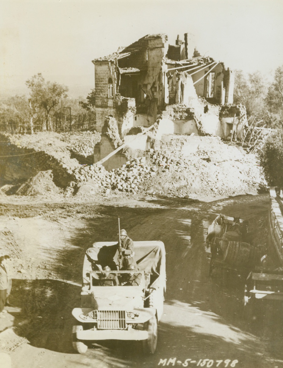 FREE FRENCH FIGHT AGAIN, 12/18/1943. SOMEWHERE IN ITALY—Rolling past the shattered wreck that was once a house, free French warriors of the Second Morocco Division speed through a war-torn Italian town on their way to the front lines. The Frenchmen are fighting, again, in Europe, for the first time since the capitulation of France in 1940, equipped with modern American weapons and clothing.;