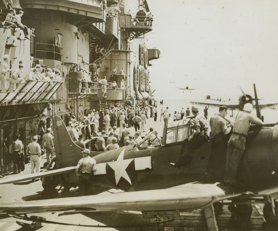 Checking in After Rabaul Raid, 12/16/1943. South Pacific – The flight deck of the Aircraft Carrier USS Saratoga, represents a neat problem in handling traffic, as planes come in after the raid on the Jap base at Rabaul, New Britain, last Nov. 5. The raid was credited with severely crippling the Nip stronghold, and it was reported abandoned after a subsequent raid. Here, a Douglas Dauntless (SBD) Dive Bomber, (foreground), is checked in while, beyond, another taxies up after landing, its prop still spinning. In the background, a third SBD comes in for a landing. Credit: U.S. Navy Official photo from ACME;