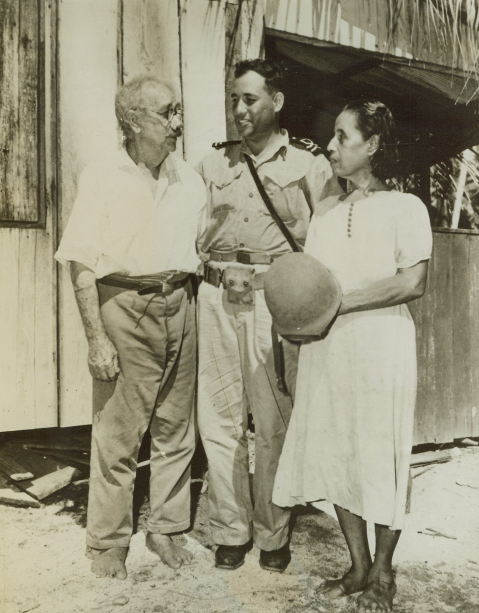 Reunion on Makin, 12/17/1943. Makin, Gilbert Islands – After nine years of separation, Lt. Bruno Raymond, Royal Australian Naval Volunteer Reserve, meets his father, Moritz (left), and his half-native mother, Maria, after going ashore on newly-captured Makin Island. Lt. Raymond, who is attached to the U.S. Navy as a pilot, was born in the Gilbert Islands. His parents lived on Makin all during the Jap period of occupation. Credit: ACME;