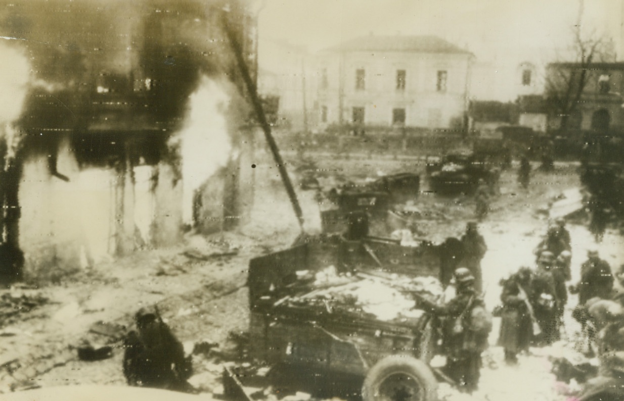 Meager Victory, 12/20/1943. Russia—After a year of almost steady retreat before the powerful Red Army, German troops managed to retake a few towns on the central Russian front. Here, according to German caption accompanying photo, are Nazi troops as they reentered Zhitomir. Truck in foreground is supposedly a mobile Red Army office. Radioed from Stockholm this morning. Credit: ACME radiophoto.;