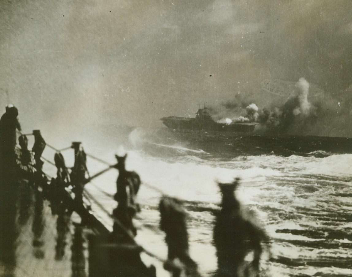 The Last of the Wasp, 10/28/1942. Southwest Pacific – Settling by the bow and listing heavily to the starboard side where three Jap torpedoes struck just forward of the “island”.  The USS Wasp is pictured in her death throes from the deck of an accompanying warship.  Since the water system was wrecked by the explosions, the fire could not be checked.Credit (Official US Navy photo from ACME);