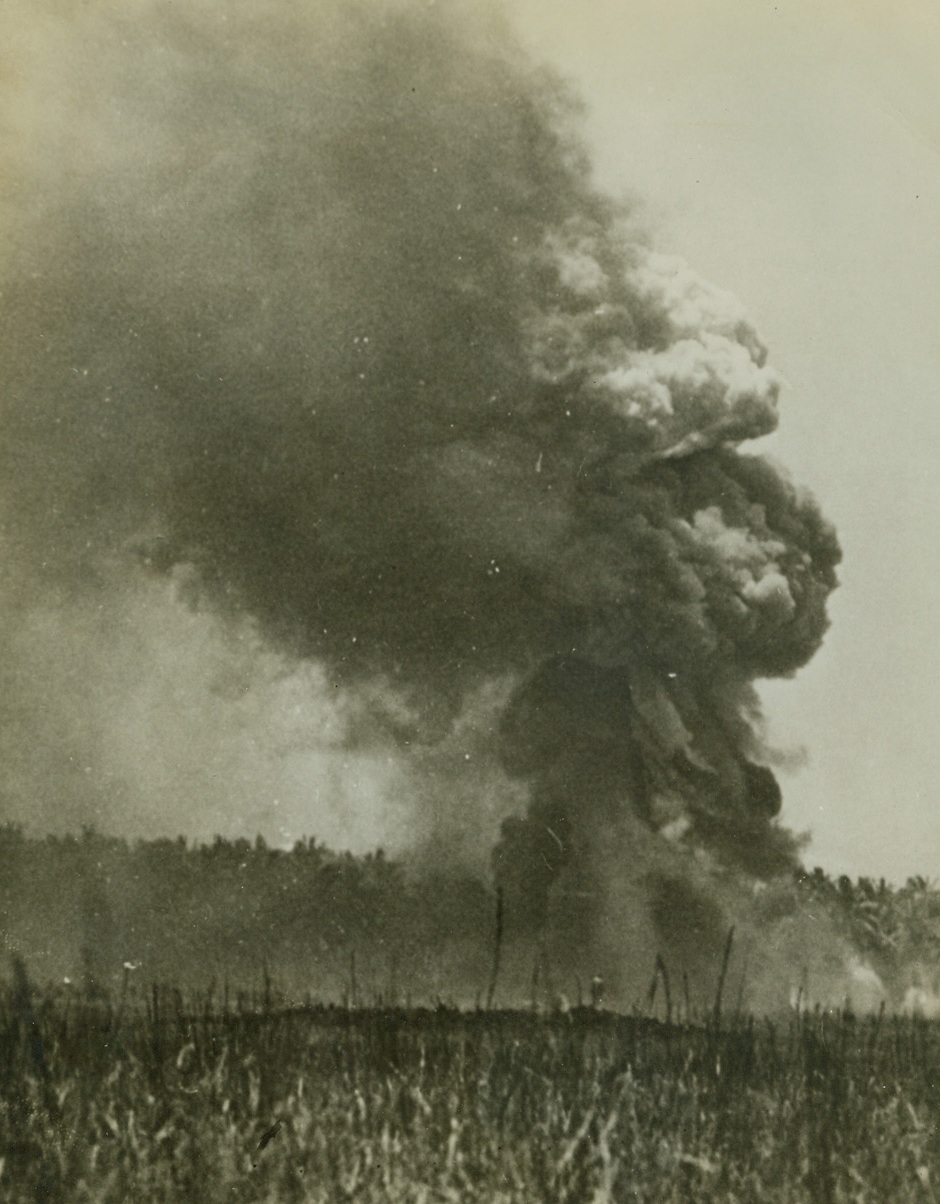 Japs Hit U.S. Gasoline Dump, 10/6/1942. A towering pillar of smoke rises from a U.S. Marine gasoline and oil supply dump on Guadalcanal Island in the Solomons, after Japanese bombers had registered direct hits, during early fighting in that area. (Passed by Navy Censors). Credit: ACME;