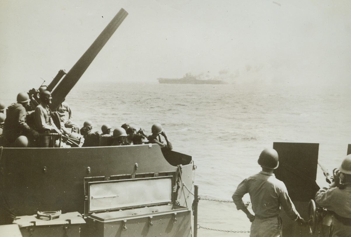 Death of the Wasp, 10/28/1942. South Pacific – Men of an accompanying warship look on sadly as the USS Wasp blazes fiercely after being struck by three enemy torpedoes on Sept. 15th.  The carrier, wrecked by explosions and flames, was finally sent to the bottom by torpedoes of a U.S. Destroyer. Credit (official US Navy photo from ACME);