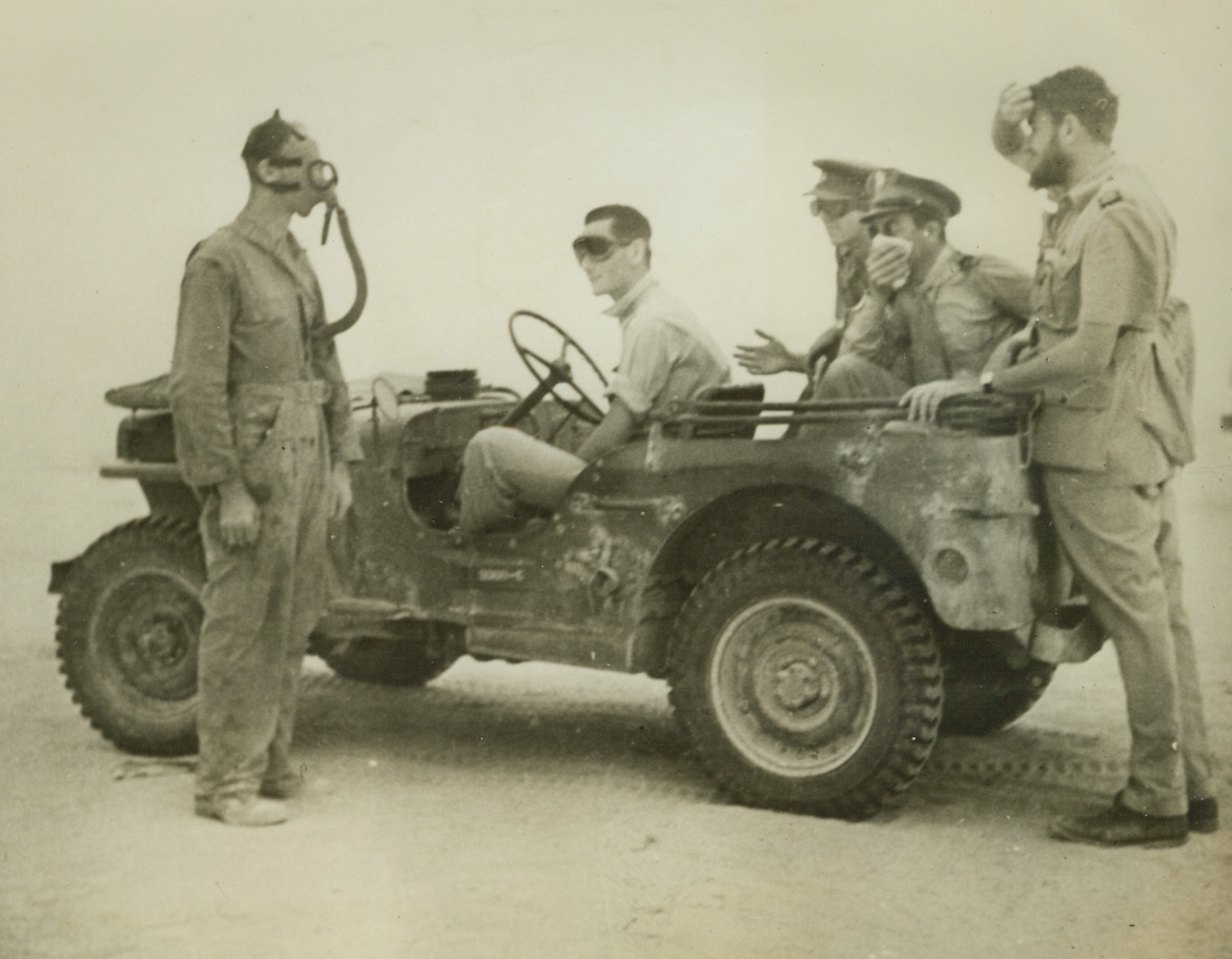 Americans Get Taste of Egyptian Sandstorm, 11/9/1942. On the Egyptian Front—An American war correspondent, Weston Haynes (right), stands behind a peep-load of American Air Forces fighting men, as the group begins to feel the full fury of a desert sandstorm. A mask, pad of cloth and goggles are used to keep stinging sand out of nose, eyes and throat. (Passed by censors).Credit: ACME.;