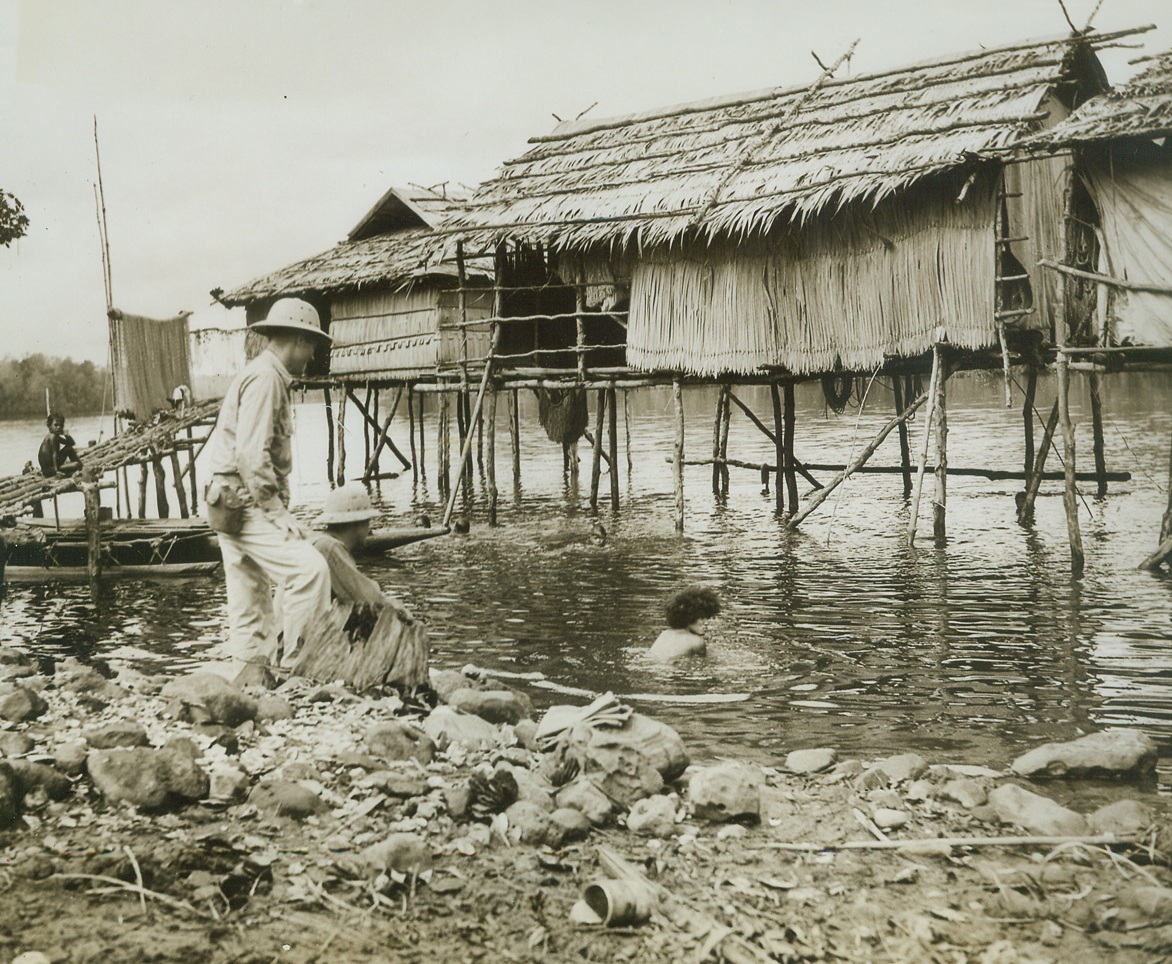 A Day Off in New Guinea, 12/29/1942. New Guinea: - It’s not all blood and sweat and toil for the American soldiers in New Guinea.  Occasionally they get a day off, and then they go sight-seeing.  Sgt. Albert Bretz, of Wadena, Minn. (left) and Sgt. John Lamping of St. Louis, Mo., wandered down to shore and found a native family swimming in their front yard - so to speak. Credit Line (ACME);