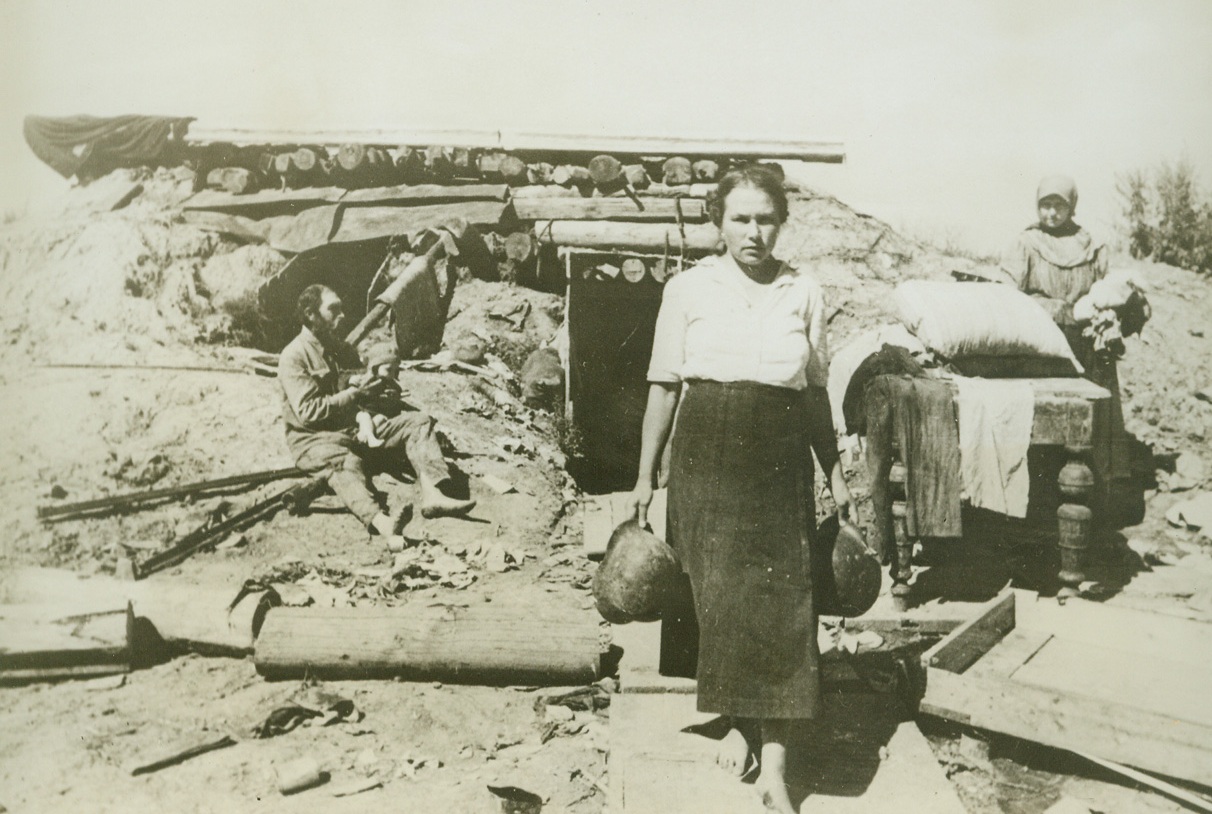 Living in German Dugouts, 12/2/1942. SOMEWHERE IN RUSSIA—Residents of liberated Russian villages, their homes destroyed, now live in dugouts that once protected Nazi forces. Latest dispatches from Russia indicate that the German High Command is pulling troops out of Stanlingrad and the offensive of the Red Army in that city is rolling along successfully. Passed by censor.Credit: ACME;