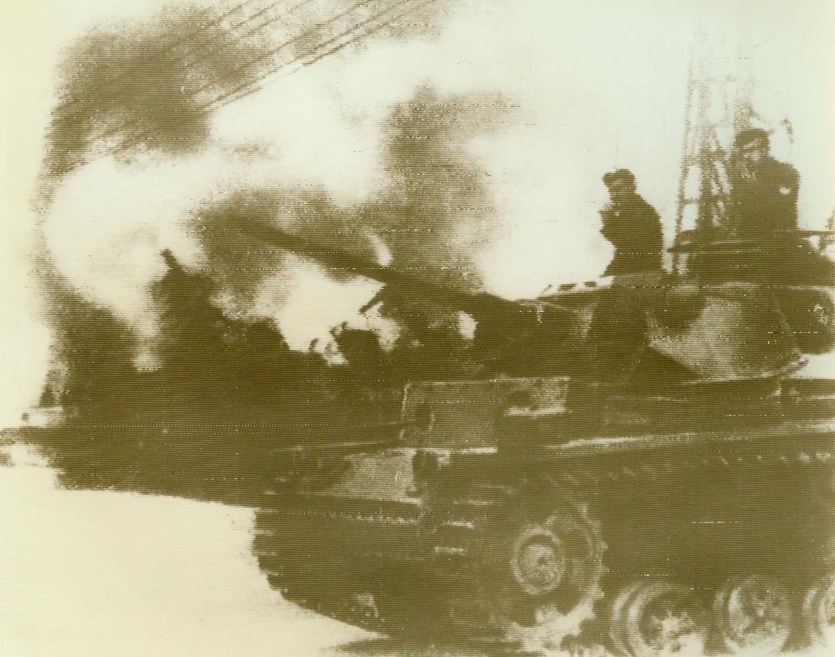 Toulon Scuttling Bared, 12/16/1942. Toulon, France – Exclusive ACME radiophoto shows a German tank arriving at the scene of the scuttling of the French fleet in Toulon harbor as a battleship burns in the background. RAF photos, taken on the day after the scuttling reveal that virtually the whole fleet was sunk. The battleship Strasbourg, although not sunk, has settled and grounded in the harbor. 12/16/42 (ACME Radiophoto);