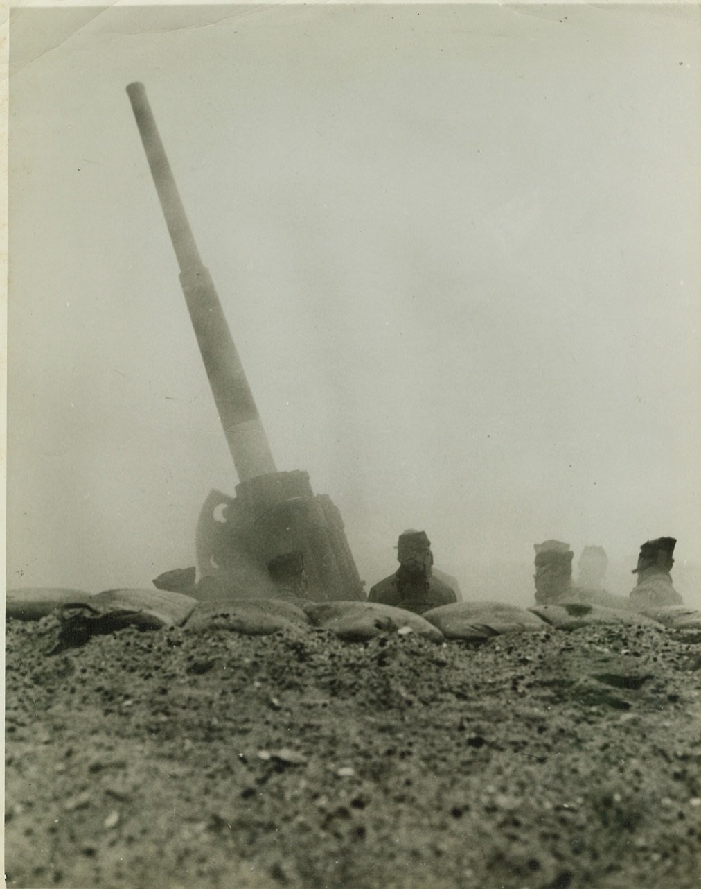 GAS ATTACK (MOCK) HITS FORT MONROE, 3/18/1942. FORT MONROE, VA. - Smoke and gas cloud the crew and emplacement of an anti-aircraft gun at Fort Monroe, during a recent simulated attack by gas-carrying planes. Note soldiers wearing masks. This was the largest actual gas demonstration to have been carried out, thus far, on the Atlantic Coast. Credit: OWI Radiophoto from ACME;