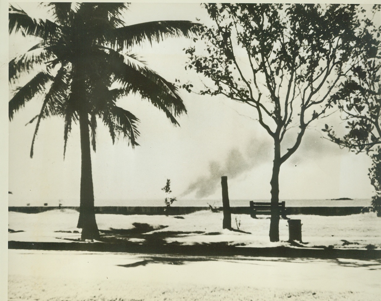 RED CROSS MERCY VOYAGE IN PICTURES, 3/26/1942. On the eve of the fall of Manila, General MacArthur cabled the American Red Cross asking for a ship to evacuate about 200 of his men, who were wounded. On Dec. 31, the small freighter Mactan was chartered by the Red Cross, and marked with Red Cross flags. It was loaded with the wounded, manned by doctors and nurses from the Philippine Red Cross chapter, and sailed early Jan. 1st, after permission had been received from the Japanese Government to pass through the war zone. This photo, and others in this set, were taken by Irving Williams, of Patchogue, Long Island, and released through the Red Cross. The wounded were taken off at Sydney, Australia. In this photo, made from Dewey Boulevard, in Manila, smoke pillars, (in background), are shown rising from the burning Naval Base at Cavite, as the Japs approached Manila. It was when it became apparent that Manila was to fall, that Gen. MacArthur asked for the “Mactan”. Credit: ACME;