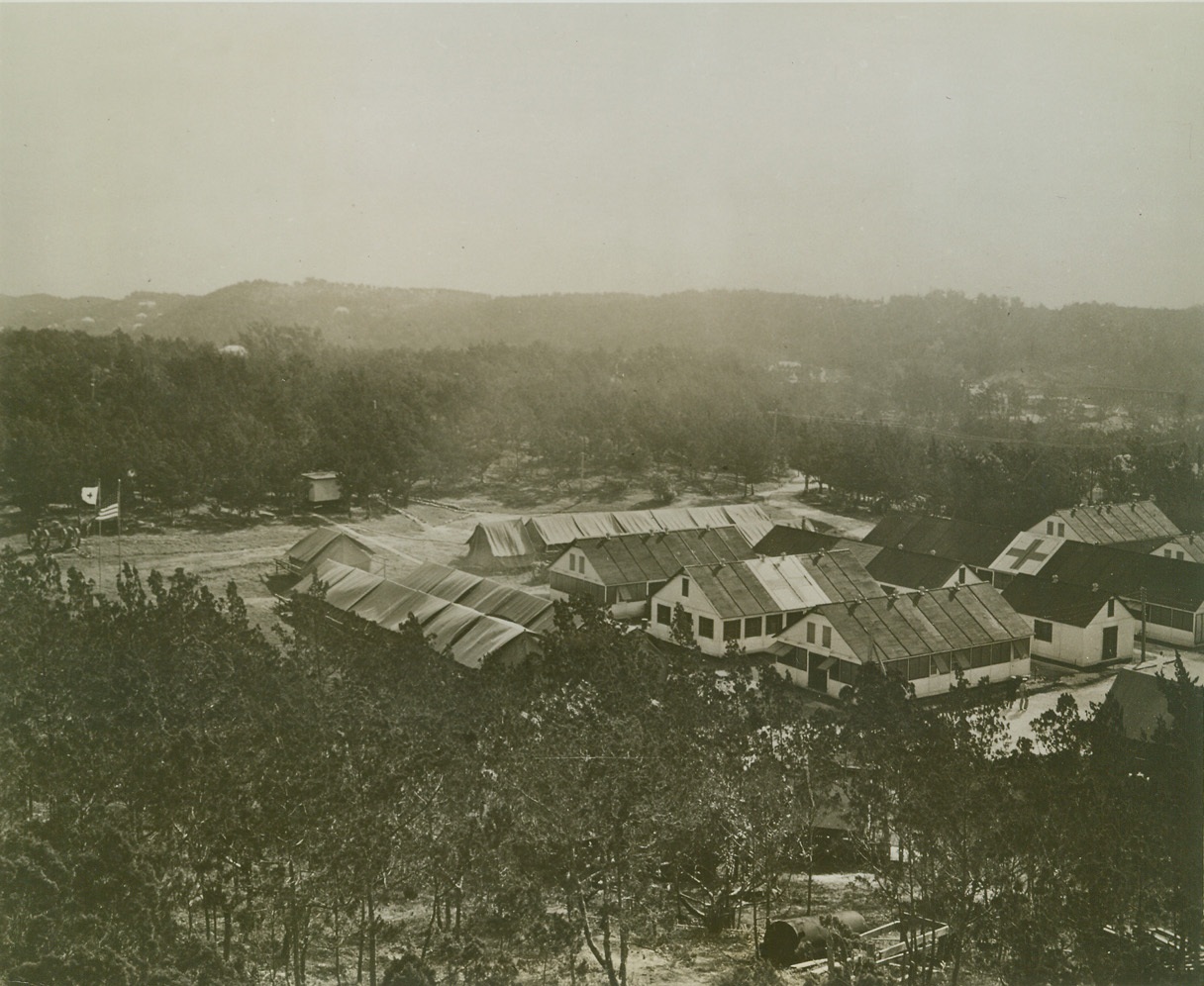 U.S. NAVAL MOBILE BASE HOSPITAL #1, BERMUDA, 3/6/1942. The U.S. Navy has a mobile hospital in Bermuda, which is plainly marked and is far removed from any military objectives. The hospital is made up from prefabricated buildings and some of the quarters are tents. Special equipment has to be used in case it is decided that the buildings should be moved. Men attached to the Navy Medical Corps are capable of setting up such a hospital but it has been learned that it’s not good economy to have the labor of construction performed by Medical Corps men unless it is a case of absolute necessity. A general view of the unit used in connection with Uncle Sam’s bases. Various field laboratories and buildings for operating rooms are all plainly marked with a red cross. Credit: U.S. Navy photo via OWI Radiophoto from ACME;