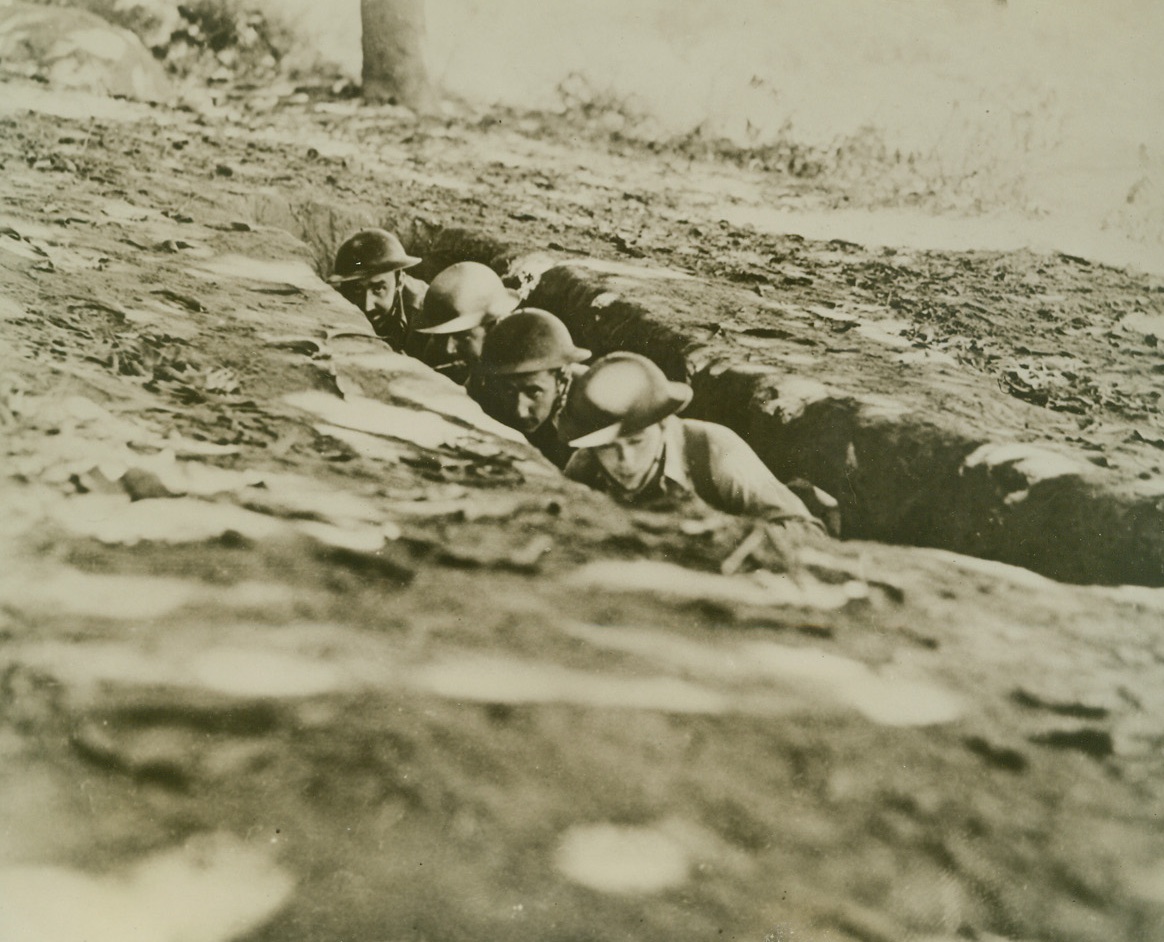 AMERICAN OFFICERS IN BATAAN FOXHOLE, 4/9/1942. This picture, one of the latest to be received from the Bataan Peninsula, now lost to American forces, shows American officers in a foxhole, ducking shrapnel fire from Japanese guns. Left to right, are: Capt. S. O. Little, Sgt. John G. Graham, Lieut. P. W. Frutiger, and Corp. R. L. Carter. Credit: U.S. Army Signal Corps photo from Acme;