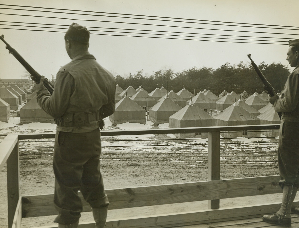 No Title. 4/2/1942. Several hundred German, Italian and Japanese nationals have been interned at Fort Meade...They live in tents of the same type used by United States troops. They dine on the same fare. The different nationalities are seperated within a high-wire enclosure. No visiting among groups is allowed. Site of the internment camp was formerly a training center for reserve officers. Photo shows a section of the camp as seen from the top of a guard house.;