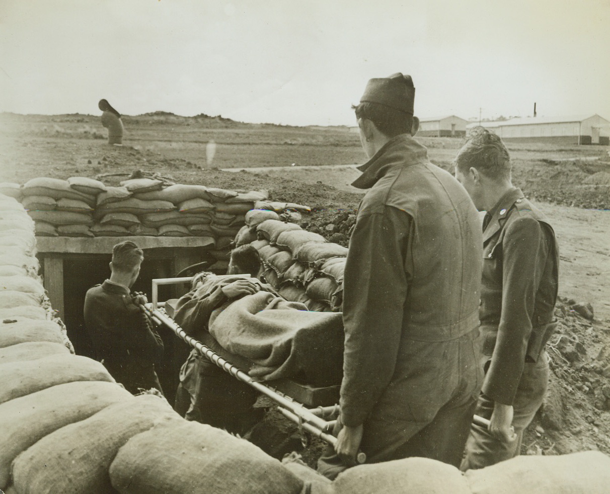 Underground Emergency Hospital on Airfield, 5/13/1942. Australia – An American pilot is carried into an underground emergency hospital by U.S. soldiers at one of the airfields Down Under. Pilot was not actually “wounded.” Credit: ACME;