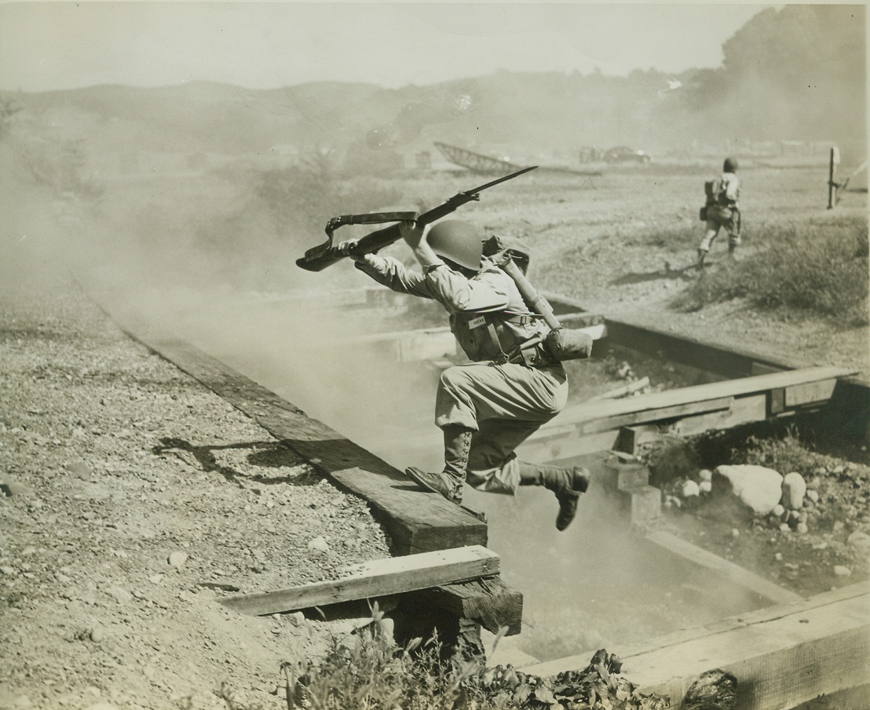 THINK HE DIDN’T MAKE IT? ---- HE DID!, 8/6/1942. WEST POINT, NY – It doesn’t look like this plebe would make this five-foot jump up out of a trench – but he did! And so did the other plebes that tackled this part of a tough, 200 yard “assault” course at West Point, Aug. 6th. The boys, carrying 22 pounds of equipment, hurdled trenches and barbed wire tangled log fences, and took bayonet stabs at dummies. The course is part of five weeks of intensive training, which precedes the plebes’ academic course at the United States Military Academy. Credit: OWI Radiophoto from ACME;