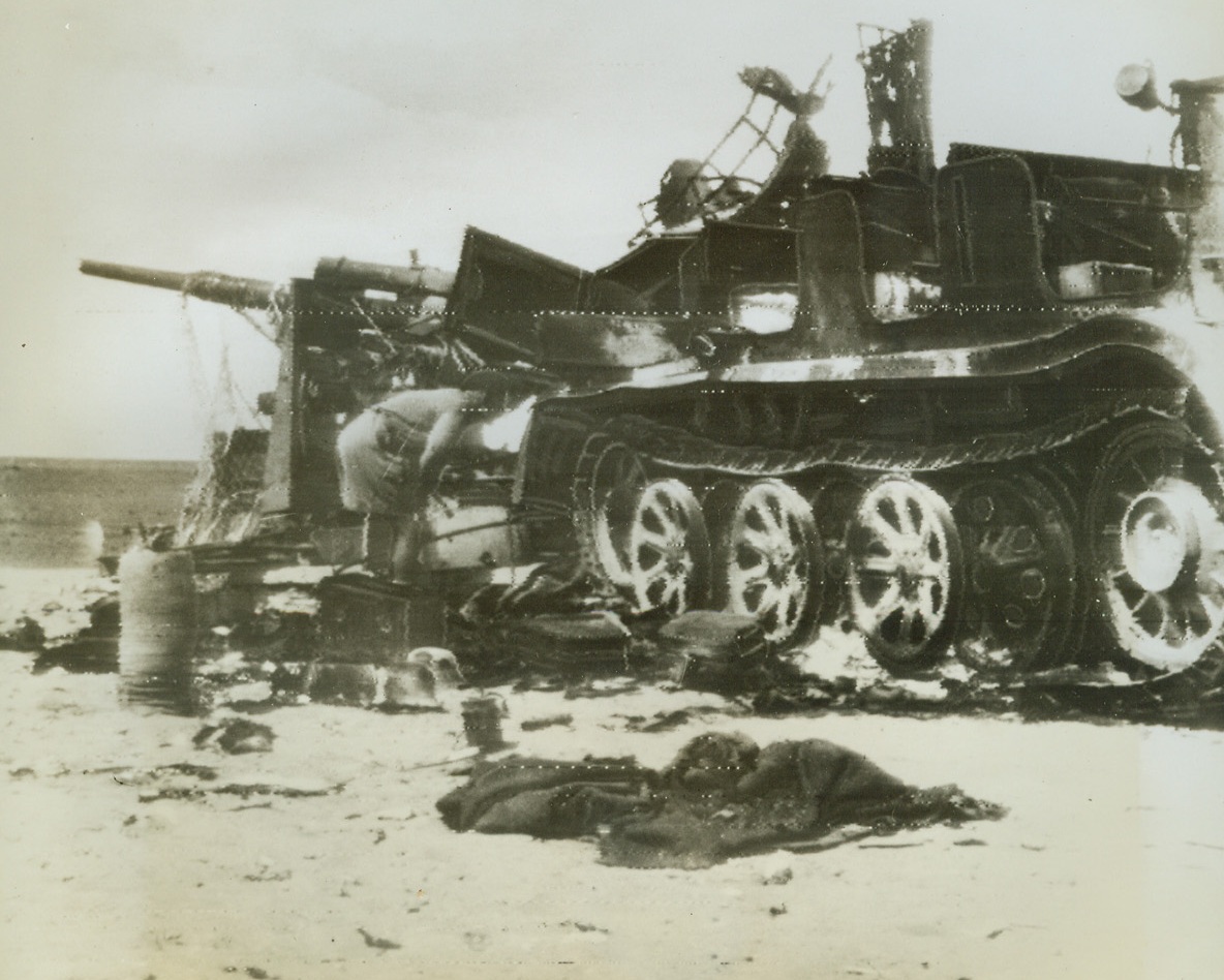 Badly Busted, 9/9/1942. Western Desert - - A British tommy gets a close look-see at this busted and battered tractor which was once used to draw the 88 mm Nazi gun in the background.  The whole outfit, which included accommodations for the German gun crew, was made scrap by direct hits of crack British artillery gunners.  Wrecks like this one are not unusual sights on the Western Desert front where Allied airmen and soldiers have successfully checkmated Rommel’s drive for Alexandria and the Suez.   Photo was radioed directly from Cairo to New York, Sept. 9th. Credit line (ACME radio photo);