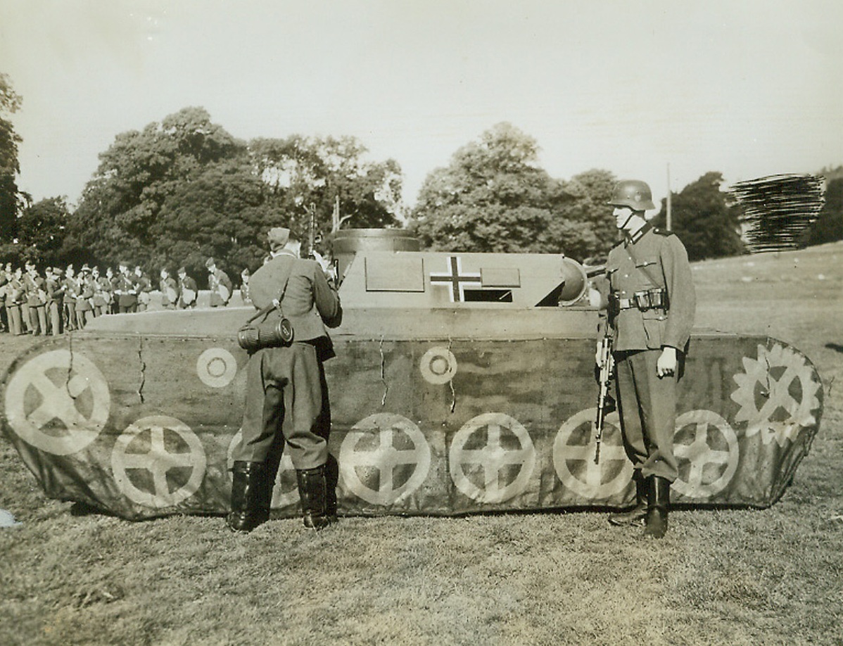 No Klieg Lights at This Preview, 9/18/1942. Northern Ireland—American armoured forces in Northern Ireland receive a demonstration from British soldiers on the various uniforms and weapons used by the Nazis so that they will have a clear picture of the enemy when they go into action. Here an American soldier (left) in German uniform peers inside a German tank as a British soldier also in German uniform looks on. (Passed by censor). Credit: ACME.;