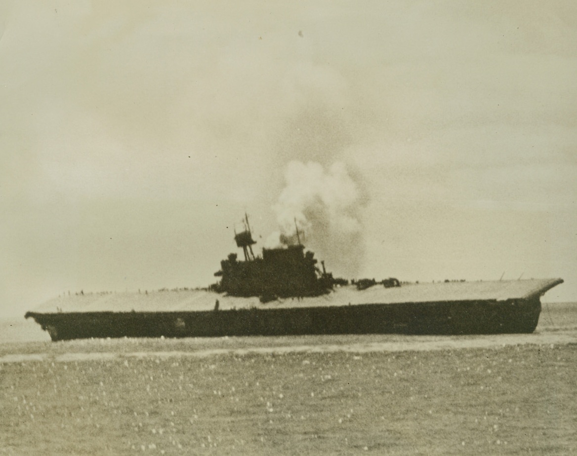 End of the Yorktown, 9/16/1942. Washington, D.C. – The flight decks are bare of planes and men as the aircraft carrier U.S.S. Yorktown, smoke billowing from her single funnel, lists heavily toward the gleaming Pacific.  About 36 Jap bombers and torpedo planes swarmed around the 19,900-ton vessel through a hail of anti-aircraft fire, and knocked it out of action at the height of the battle of Midway island on June 4th.  Even then it was thought that salvage would be possible, but a Jap sub sent two more torpedoes into her side and the veteran of the Coral sea battle finally capsized and sank on June 7th.  Photos and story on the sinking were officially released by the Navy today.Credit Line (Officially U.S. Navy photo from ACME);