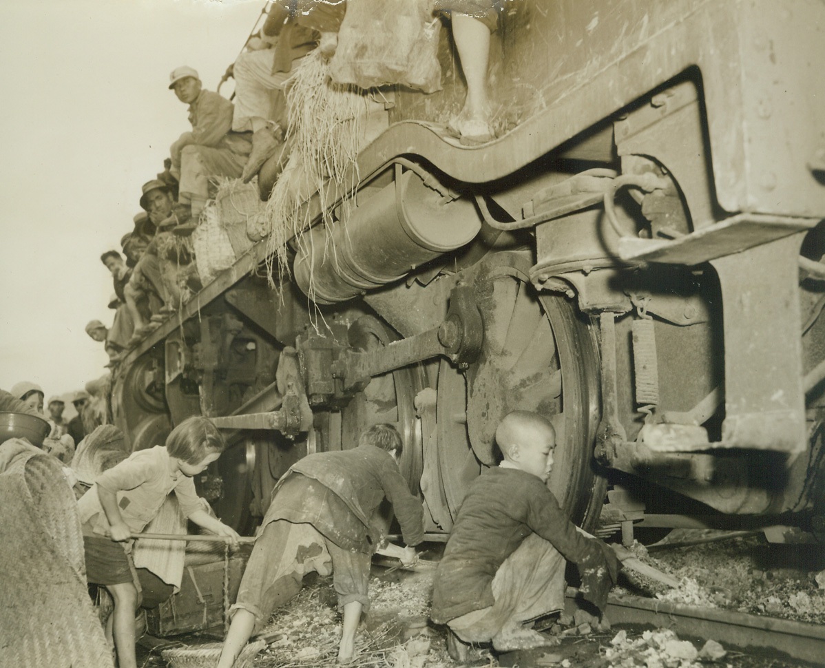 China’s Human Cargo, 11/10/1944. Eastern Front, China – Masses of humanity, united in one common purpose – flight for life—cram the railroads and highways leading from China’s Eastern front, as the instinct for self preservation sends them fleeing from Jap terror.  Simple peasants they are, familiar with only the ways of simple folk like themselves, but they know the atrocities of the Japs, rather than live under the yoke or the rising sun, they choose to suffer hardship, and even death, to evade them.  Trains leaving Liuchow are packed from the rails to the tops of the cars, and all available vehicles fill the highway as shown in this unusual and dramatic series of photos made by Frank Cancellare, ACME photographer for the War Picture Pool  On the heels of the evacuees follow constantly the fear of the dread typhus and cholera epidemic but still they go onward. New York Bureau As this train locomotive, filled on all sides with refugees and their scant belongings, stops for a short time, young children rush to scoop out the hot ashes from beneath the engine.  They will be used for heating purposes.  Photo by ACME photographer, Frank Cancellare, for the War Picture Pool. Credit –WP- (ACME);