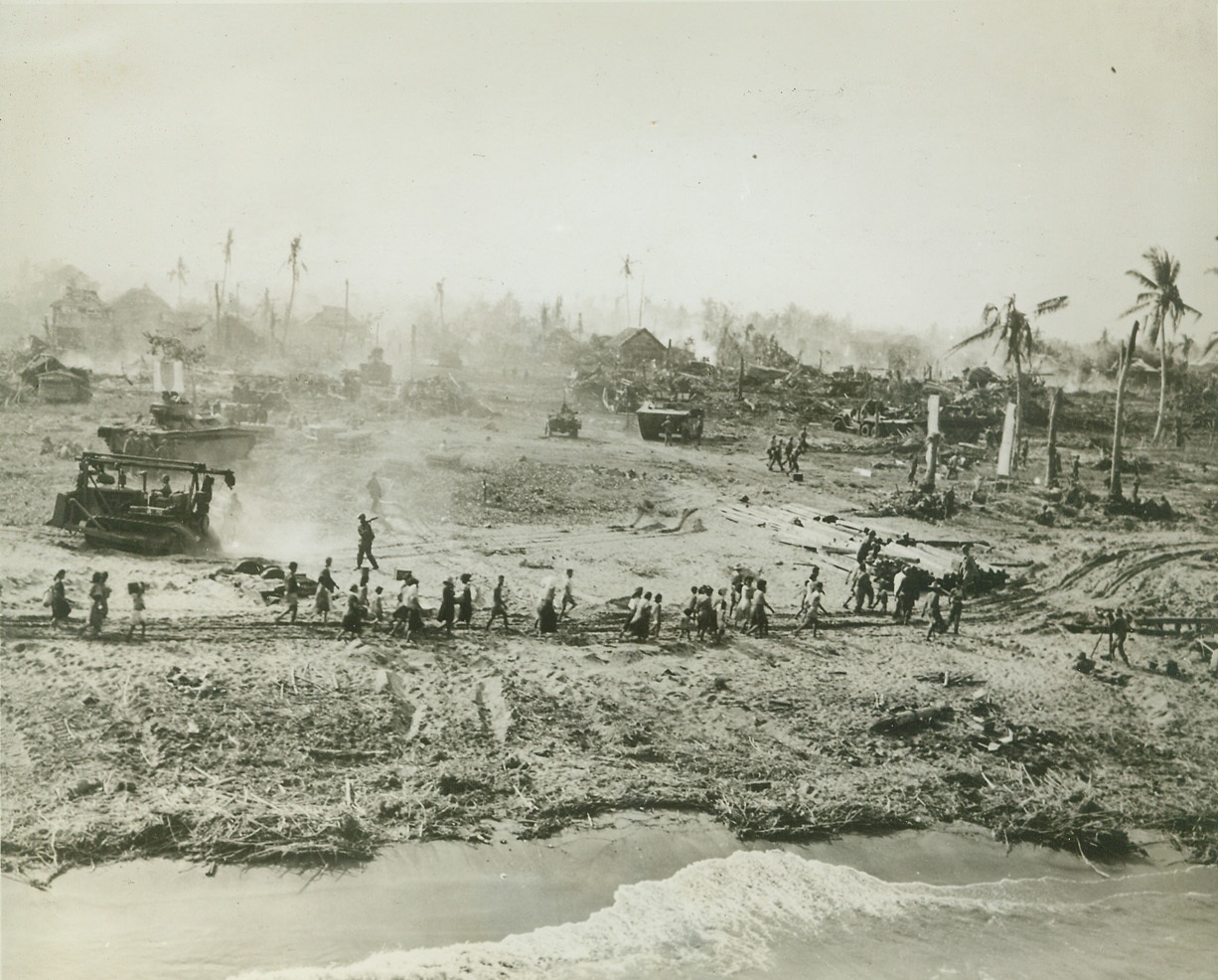 Natives Seek Safety With Yanks, 11/1/1944. PHILIPPINES -- On a smoldering beach of Leyte Island, Philippine natives follow American infantrymen to safety. Navy set up evacuation centers in safe areas where food and medical attention was given the frightened native people. Credit (Coast Guard Photo From ACME);