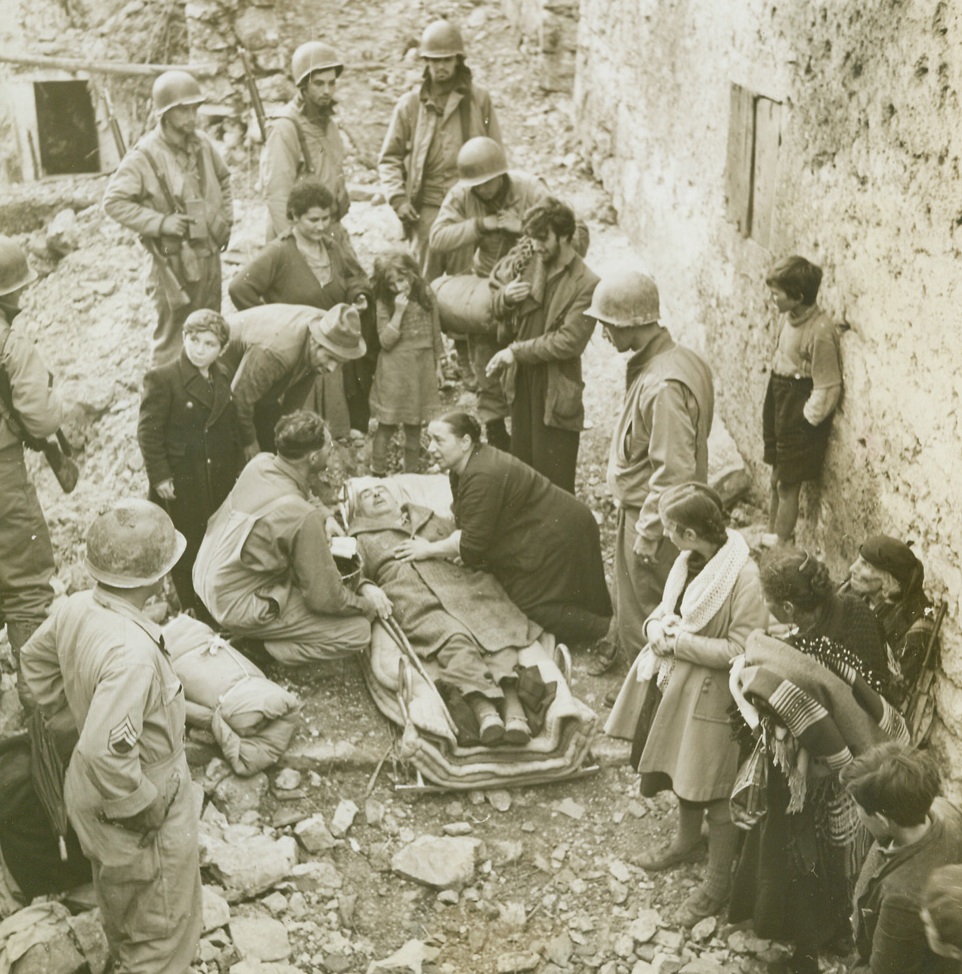 No Title. LAGONE, ITALY—Scene of many days of bitter fighting, the tiny mountain town of Lagone fell to the warriors of Lt. Gen. Mark Clark’s fifth Army, and the smoke of battle had hardly ceased before hundreds of natives flocked down from the hills to return to their homes. The pathos of their tragic homecoming to the wrecked, blasted buildings is recorded in this series, made by ACME correspondent Bert Brandt for the war picture pool. Non-combatants all, these men, women and children find that war is a very personal experience that has left them with a deep, grim hatred for the Germans.  New York Bureau An old man, who was beaten by the Germans when he protested against being driven from his home, lies on a stretcher after being carried from the hills. His wife leans over the 65-year-old Italian, telling American Soldiers that her husband will never walk again. Credit:  ACME photo by Bert Brandt, War Pool correspondent.;